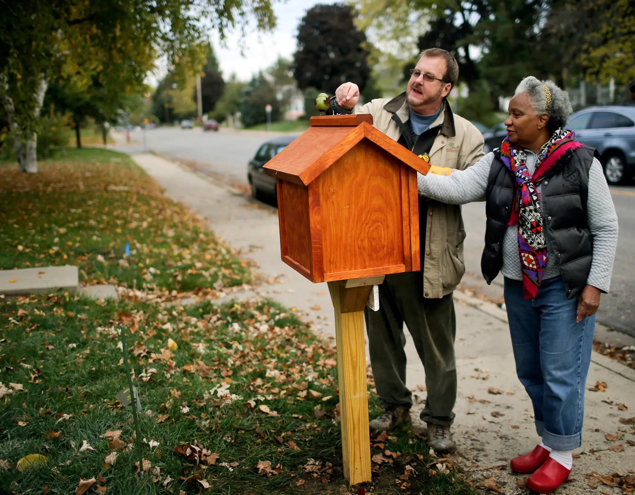 Todd Bol, o criador de Little Free Libraries, em 2013 com Eddye Watkins, que hospedou uma caixa feita pelos Amish em seu quintal em Minneapolis. O Sr. Bol considerava as bibliotecas como parte do tecido conectivo das comunidades.Crédito...David Joles/Star Tribune, via Associated Press