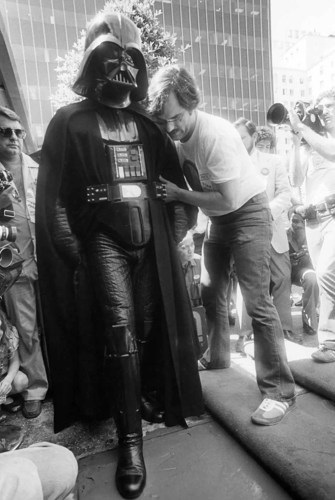 O publicitário de “Star Wars”, Charles Lippincott, com um ator vestido de Darth Vader enquanto ele deixava sua pegada no cimento do lado de fora do Grauman's Chinese Theater, em Hollywood, em 1977.Crédito...via Lucasfilm