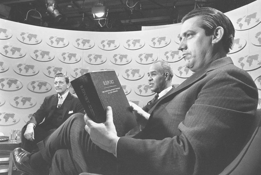 O senador Fred R. Harris (D-Oklahoma) segura uma cópia do relatório da Comissão Consultiva Nacional sobre Distúrbios Civis enquanto ele e outros dois membros da comissão discutem o estudo no programa de rádio e televisão "Issues and Answers", em Washington, 3 de março de 1968. (Bob Daugherty/AP)